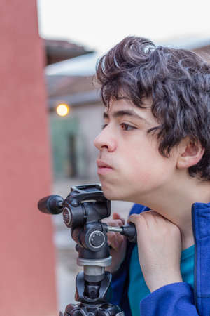 teenager kidding with a tripod in the courtyard of an old houseの写真素材