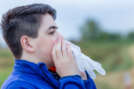 close up of young boy in countryside blowing in a disposable  plastic glove to inflate itの写真素材