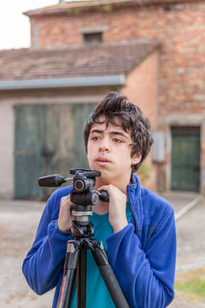 teenager kidding with a tripod in the courtyard of an old houseの写真素材