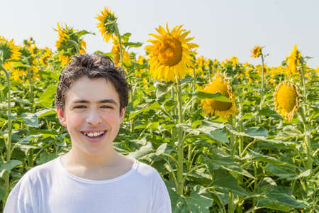 Natural and healthy living - Caucasian boy smiling in front of a field of sunflowersの写真素材