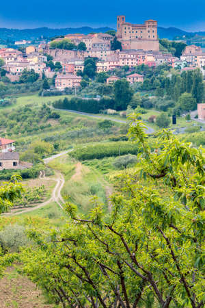 Castle in medieval village and cultivated fields and rows of fruit trees in the hills of Emilia Romagna countrysideのeditorial素材