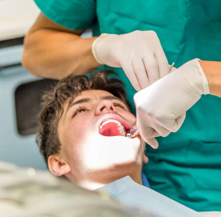 guy on the dentist chair while the orthodontist is checking the brackets of edgewise dental...