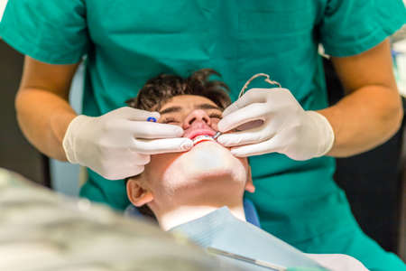 guy on the dentist chair while the orthodontist is checking the brackets of edgewise dental...