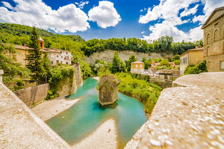 the serenity of a quiet village in the hills of Romagna countryside in Italy, while the cool waters of a placid river bathe the hamletの写真素材