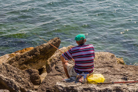 old fisherman on the rocksの写真素材