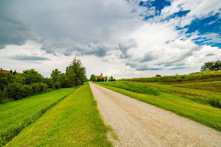 dirt road to eighteenth-century church in the quiet green Italian countrysideの写真素材