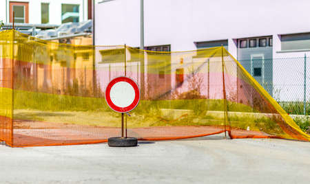 dirty and worn access prohibition sign with a white circle on a red background on a pedestal made from an old tire place to defense of a construction siteの写真素材