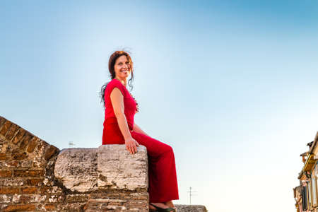 Classy woman sitting on ancient bridge in Comacchio, a village to visit in Italy, also called The Little Veniceの写真素材