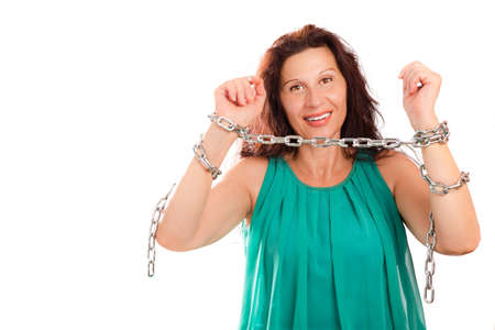 Charming mature woman with aged skin, wrinkles and other defects breaking chains around her wristsの写真素材