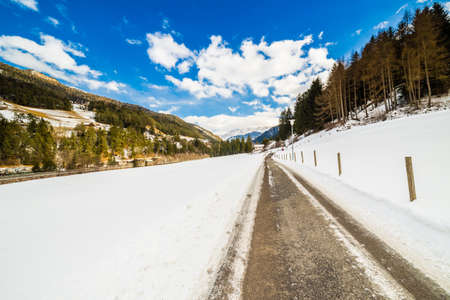 country road leading through a winter mountain landscape.