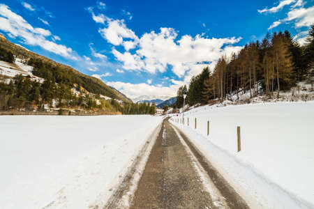 country road leading through a winter mountain landscape.の写真素材