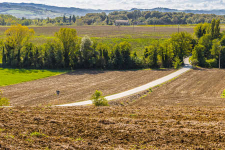 serpentine road through the plowed fields of the countryside of Tuscany and Emilia appenineの写真素材