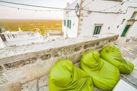 The Middle Eastern atmosphere of light green armchairs in an alleyway in Ostuni, The White Cityの写真素材