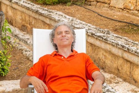 retired senior man resting blissfully lying on the recliner in the gardenの写真素材