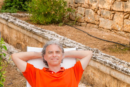 retired senior man resting blissfully lying on the recliner in the gardenの写真素材