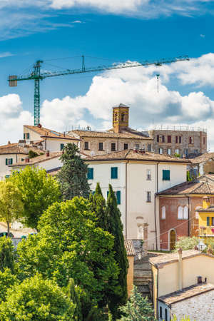 panorama of medieval village under construction in the countryside of Romagna in Italy with worker on the roofの写真素材