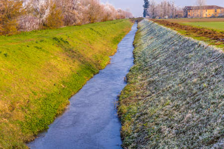 frozen irrigation canal in droughts in winter in the Italian countrysideの写真素材