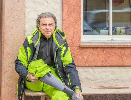 middle aged man sitting and wearing ski suitの写真素材