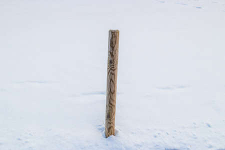 wooden pole on background of ground covered by snowの写真素材