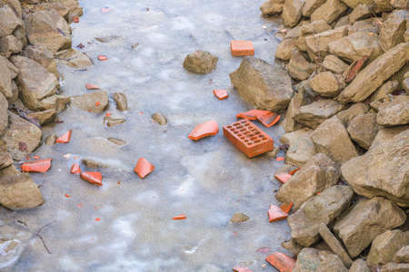 broken red bricks on frozen water of irrigation channel in the countryside of Emilia Romagna in Italyの写真素材