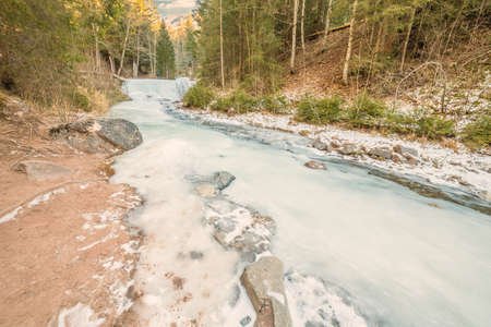 frozen brook in the forest in the mountainsの写真素材