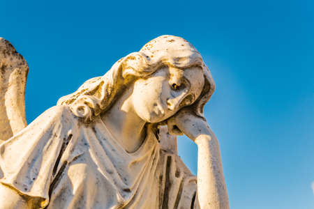 statue of sad and grieved angel looking down and sustaining her reclined head with handの写真素材