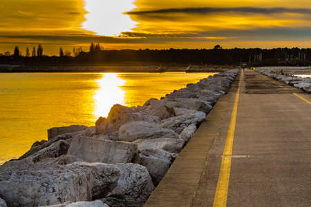 sunset on the pier paved road leading to the coastの写真素材