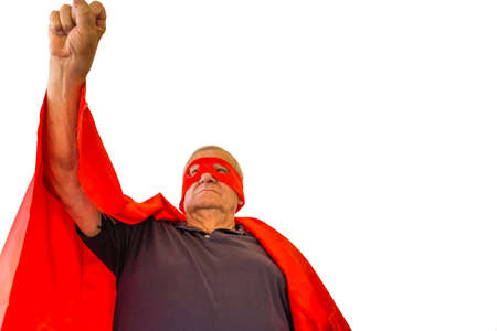 view from bottom of old man dressed as superhero sticking chest out, raising arm and showing himself triumphant and powerful while looking beyond the horizonの写真素材