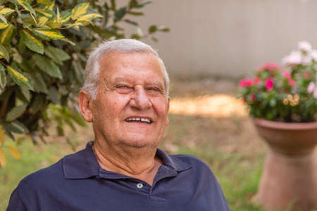 portrait of happy senior citizen in green garden of his homeの写真素材