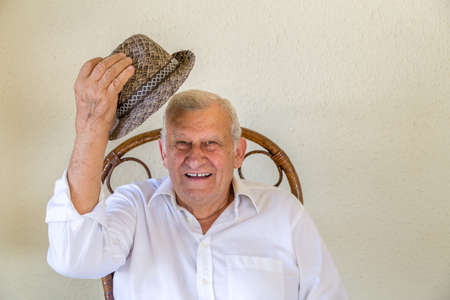 Old man holding his hat as greeting signの写真素材