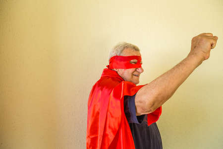 Old man dressed as superhero raising fist showing power