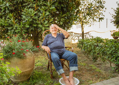 senior man having footbath in the home garden on a hot summer dayの写真素材