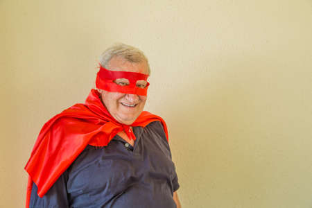 smiling old man dressed as fun superheroの写真素材