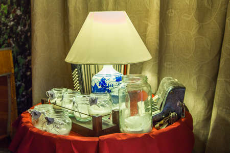 vintage table with candles in jars, old musical instruments and lampshades on curtain backgroundの写真素材