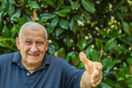 elderly man opening arms to hug on a green backgroundの写真素材