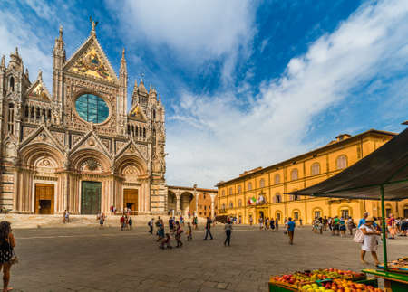 fruit stand among tourists in  square of Siena in front of Cathedral under the sun of Tuscany in Italyのeditorial素材