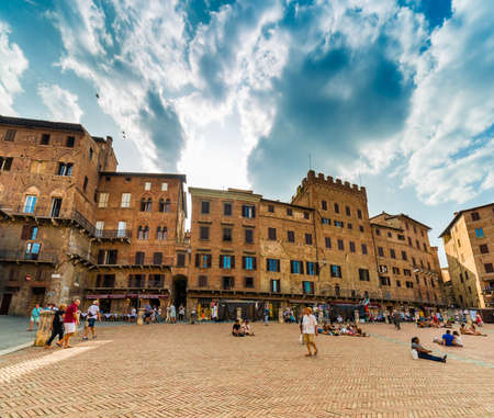 relaxing tourists enjoying main square in Siena, Italy under the sun of Tuscanyのeditorial素材