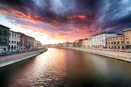 Colorful red and blue scenic sunset sky with clouds on river in Pisa, Italyの写真素材