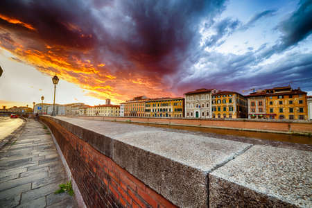 Colorful red and blue scenic sunset sky with clouds on river in Pisa, Italyの写真素材