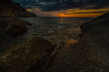 Scenic coastal sunset with orange light on island of Elba