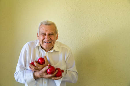 elderly man holding some pomegranatesの写真素材
