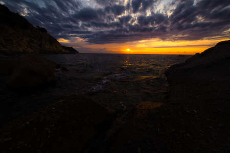 Scenic coastal sunset with orange light on island of Elba