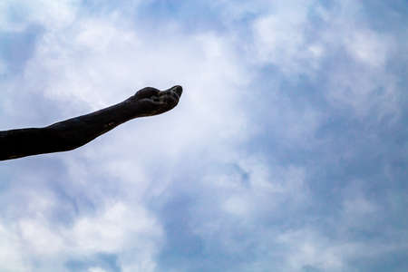 hand of bronze statue stretched out to the skyの写真素材