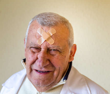 sad old doctor with patches on the foreheadの写真素材