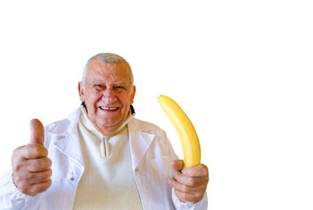 Old country doctor smiling while showing thumbs up and holding a large  bananaの写真素材