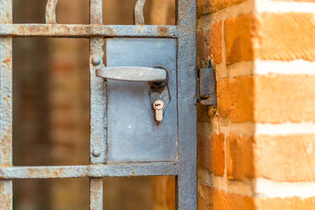 Lock with handle in old door with rusty iron grate on brick wallの写真素材