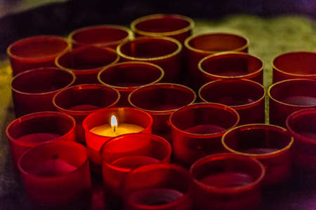 one candle burning amongst extinguished onesの写真素材