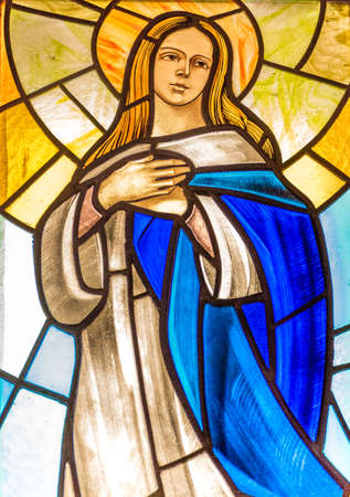 LUGO (RA) - FEBRUARY, 21 2018: The Blessed Virgin Mary holding hands on chest in a stained glass in country churchのeditorial素材