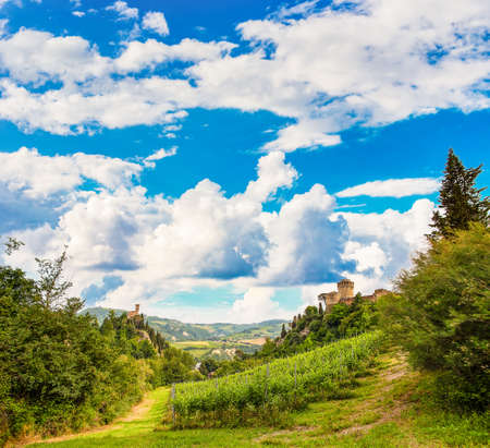 Clouds on medieval village in green country valley in Italy