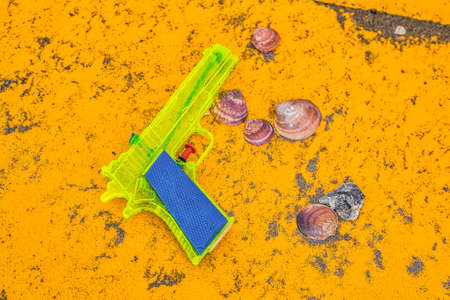 water gun and shells on yellow background